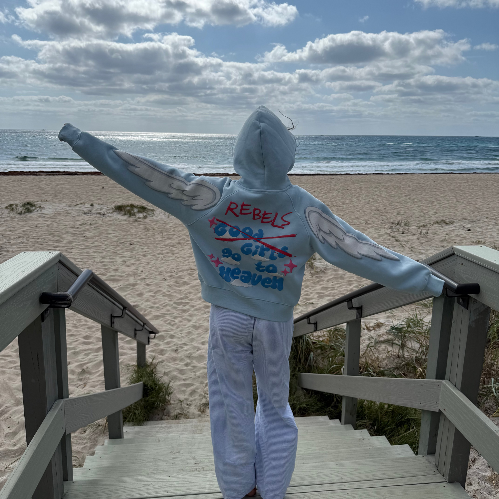 Person wearing a hoodie with text on a beach